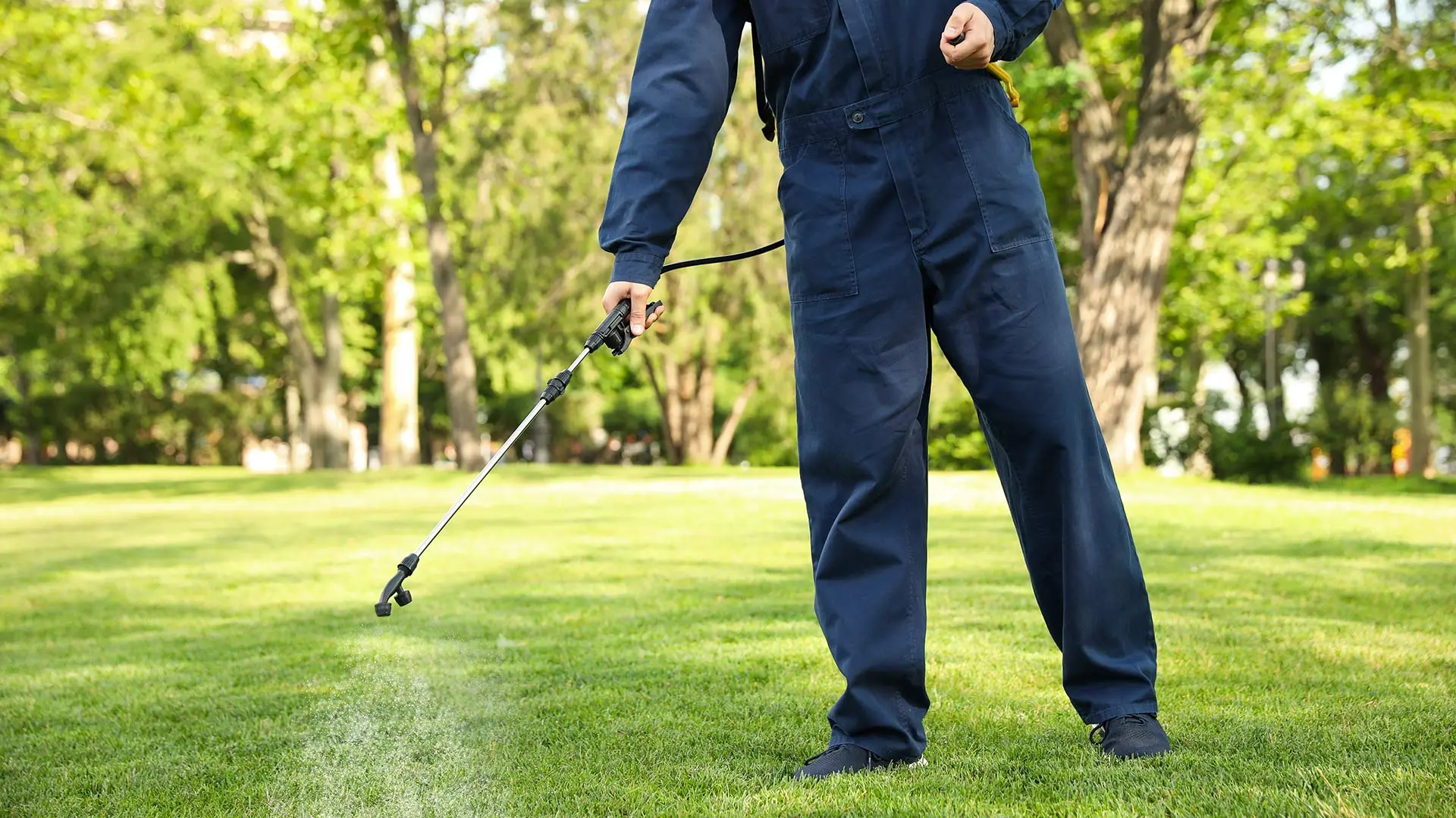 Lawn care technician spraying preventative summer patch treatment by a home in Adel, IA.