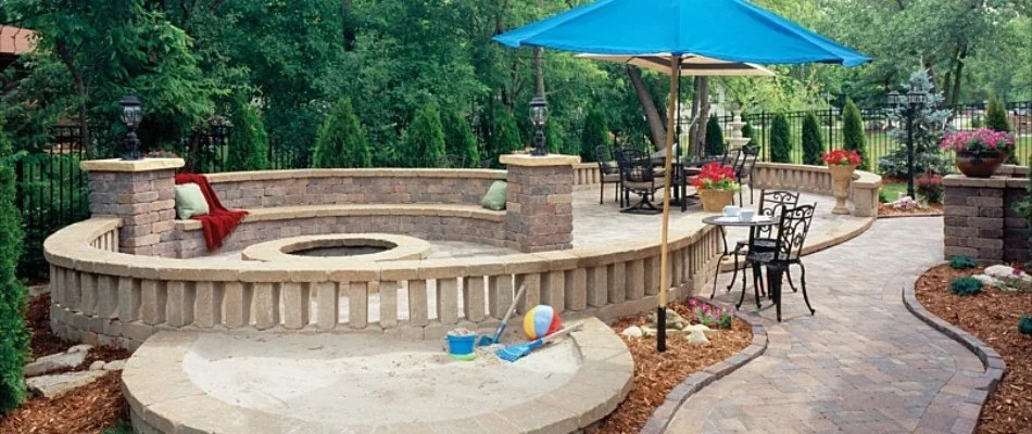 Patio area with a retaining wall and a fire pit in Greater Southside, IA.